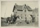 This is the home of George Barnes. He is seen here with his team of horses. The lady is Laura (Barnes) Baker. The man with the bowl is Fred Hamblin, at far right is Bill Maughan.